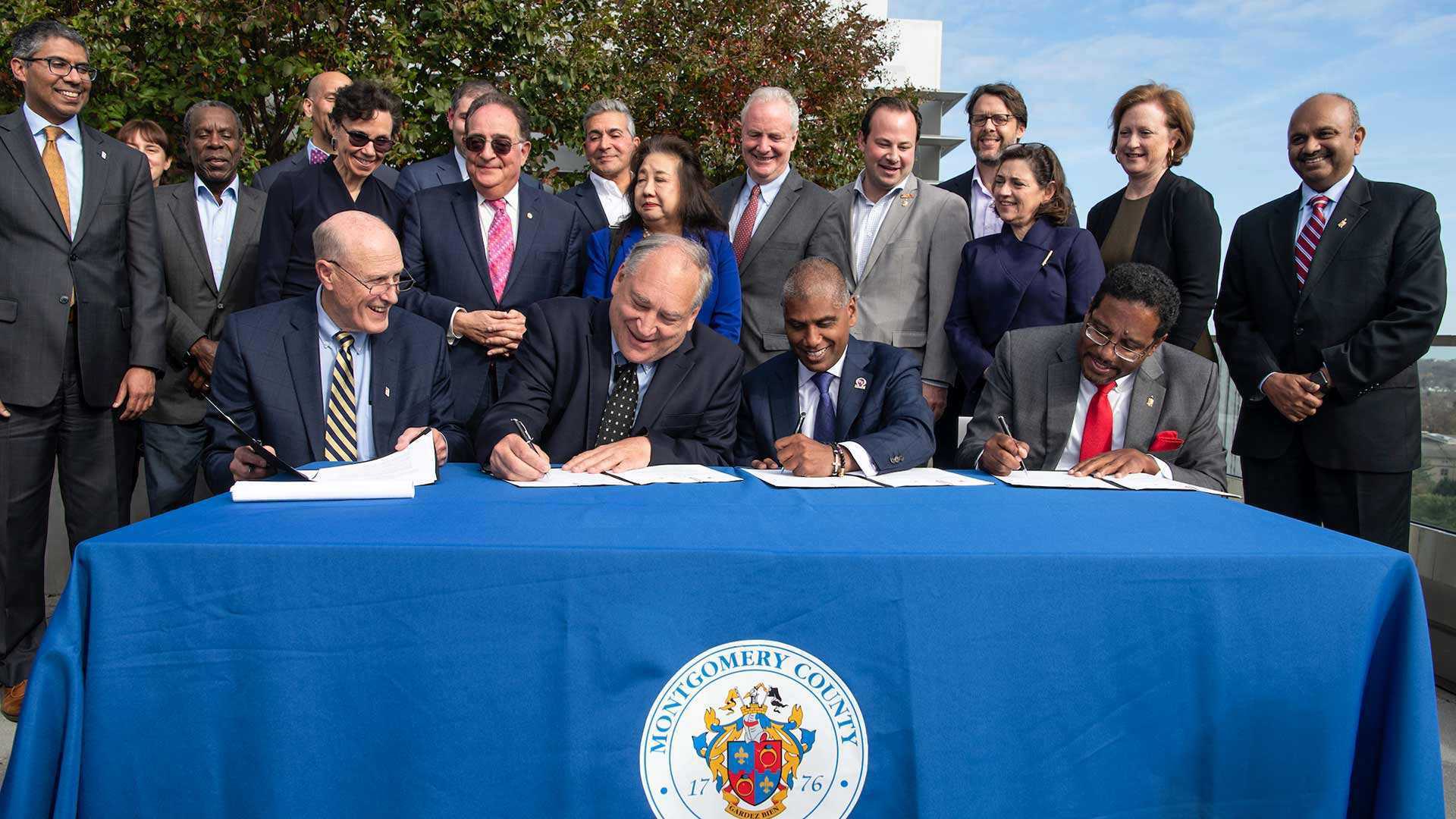 A group of individuals signing a piece of legislation into law