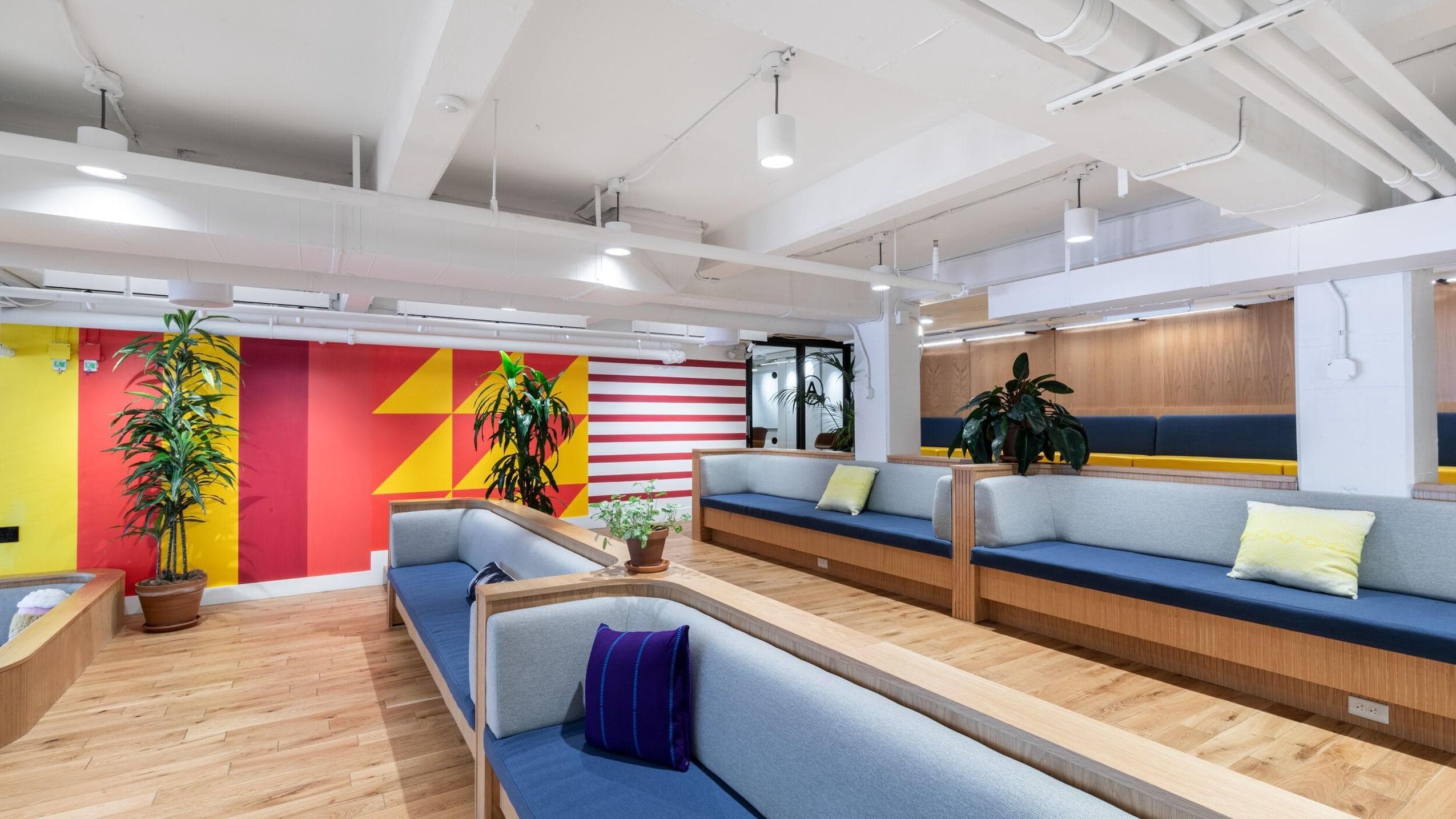 WeWork Space mezzanine aria: Long bench style couches with soft pillows, and wood furnishings.