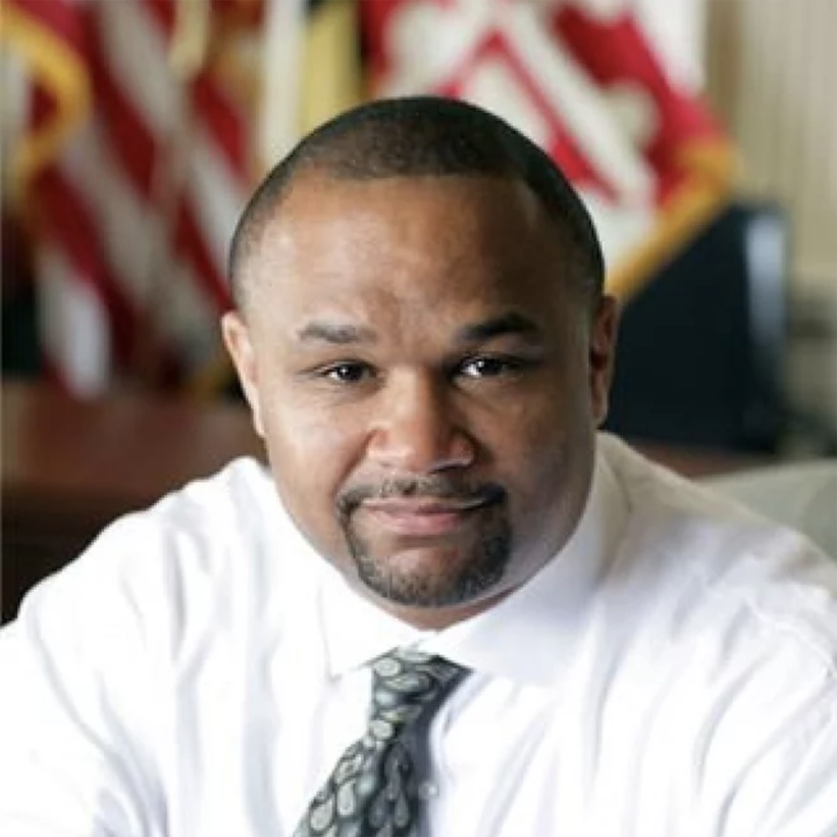 Full color headshot of Dereck Davis smiling wearing a white dress shirt and dress tie