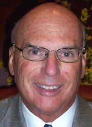 Full color photo of Edward Kasemeyer smiling wearing a gray blazer and tie.